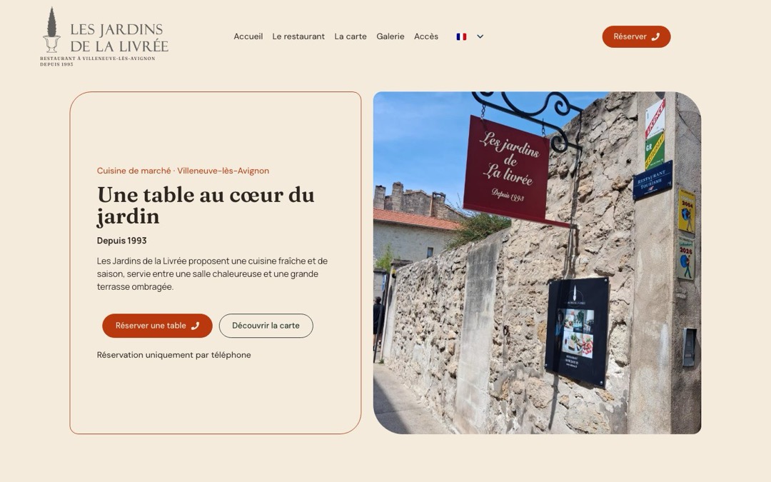 Accueil du site du restaurant Les Jardins de la Livrée : titre « Une table au cœur du jardin » à côté d’une photo de l’enseigne sur un mur de pierre