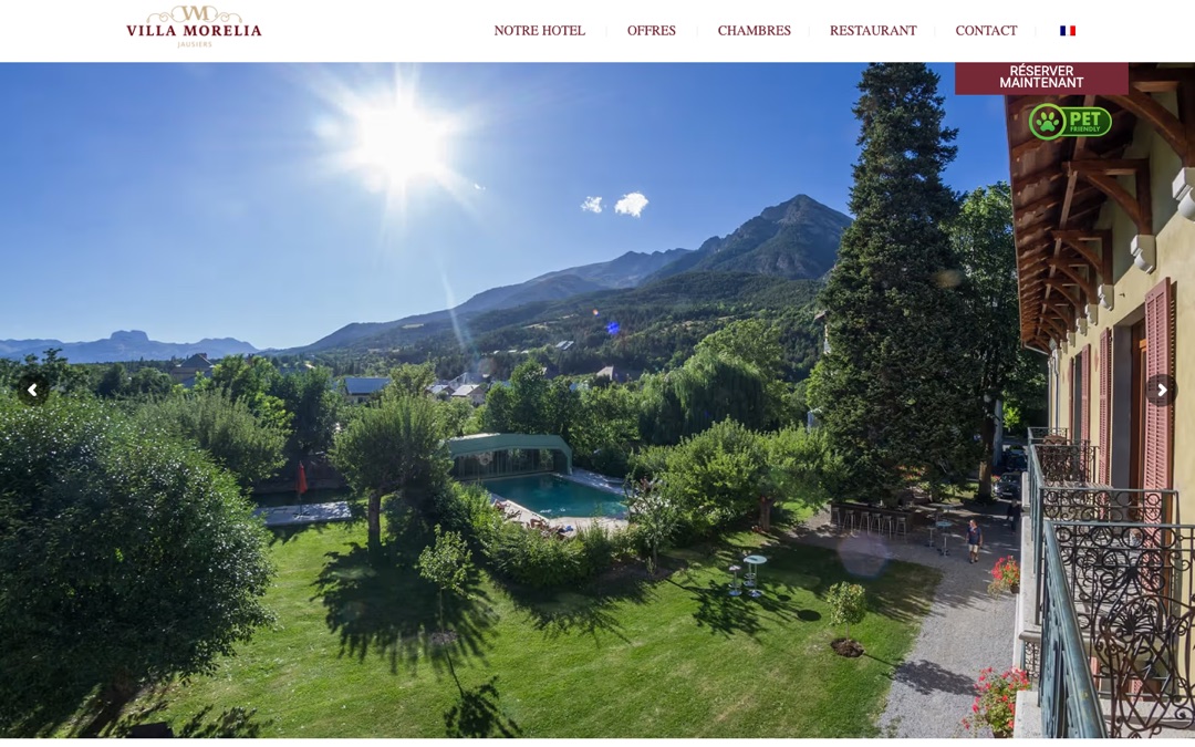 Accueil du site de la Villa Morelia : vue du parc, de la piscine et des montagnes depuis un balcon, menu en haut et bouton « Réserver maintenant »