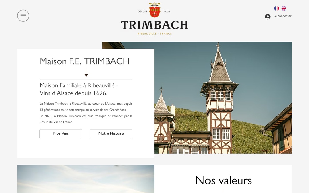 Accueil du site de la Maison Trimbach : logo au blason rouge, texte « Maison familiale à Ribeauvillé, vins d’Alsace depuis 1626 » et photo d’une tour à colombages au milieu des vignes
