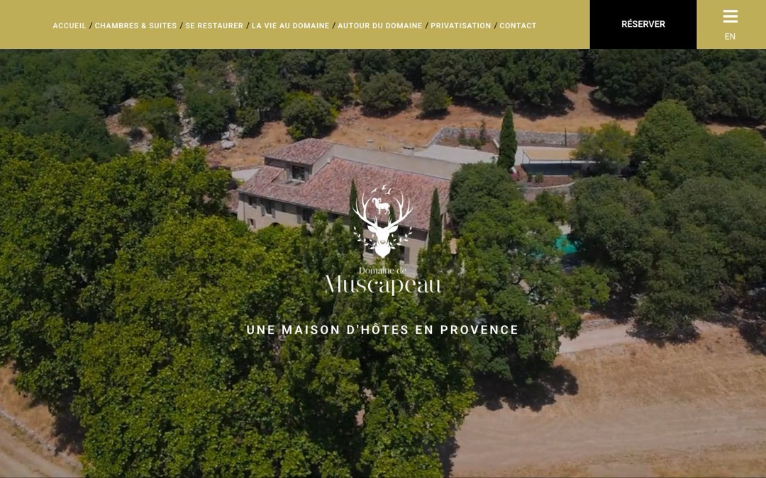Accueil du site du Domaine de Muscapeau : vue aérienne du domaine entouré d’arbres, titre « Une maison d’hôtes en Provence » et bouton « Réserver » en haut à droite