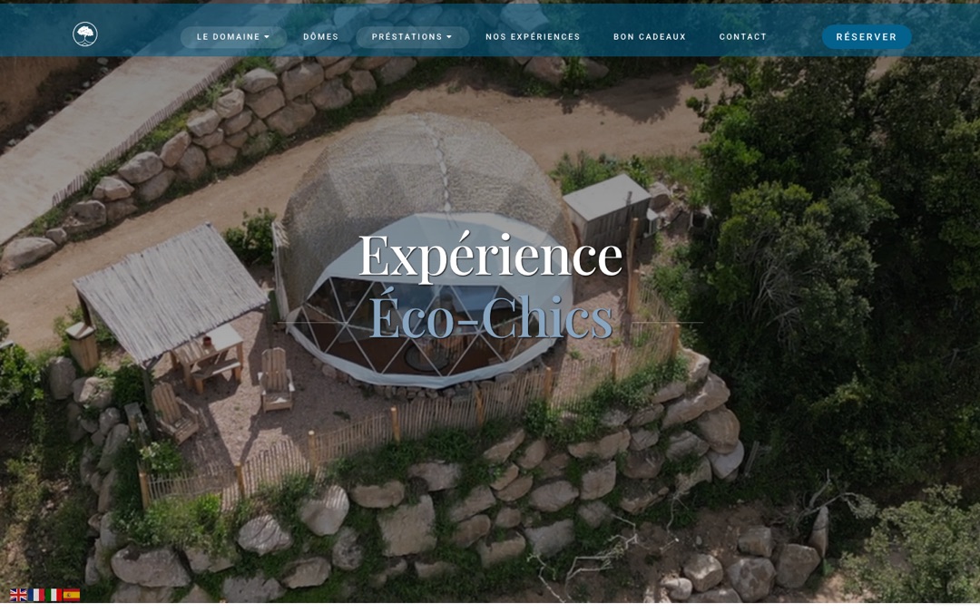 Accueil du site du Domaine de Sonia : vue aérienne d’un dôme posé sur un socle de pierres au milieu de la végétation, avec le titre « Expérience Éco-Chics » et un bouton « Réserver »