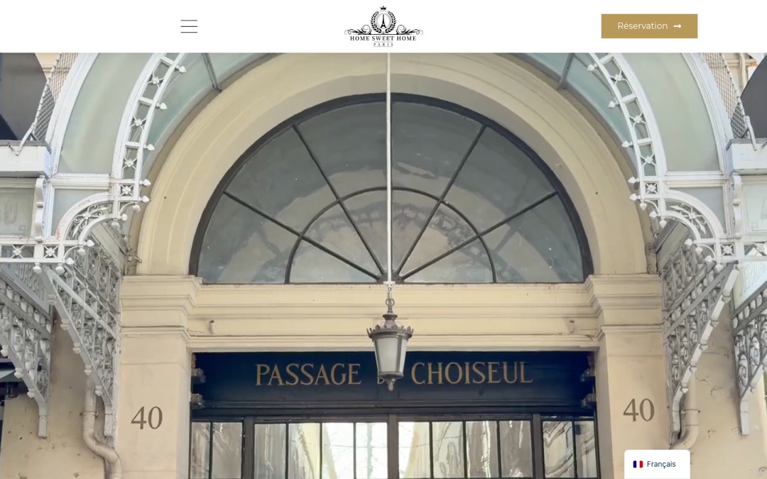 Accueil du site Home Sweet Home Paris : photo plein écran de l’entrée du Passage Choiseul, logo centré, menu à gauche et bouton « Réservation » à droite