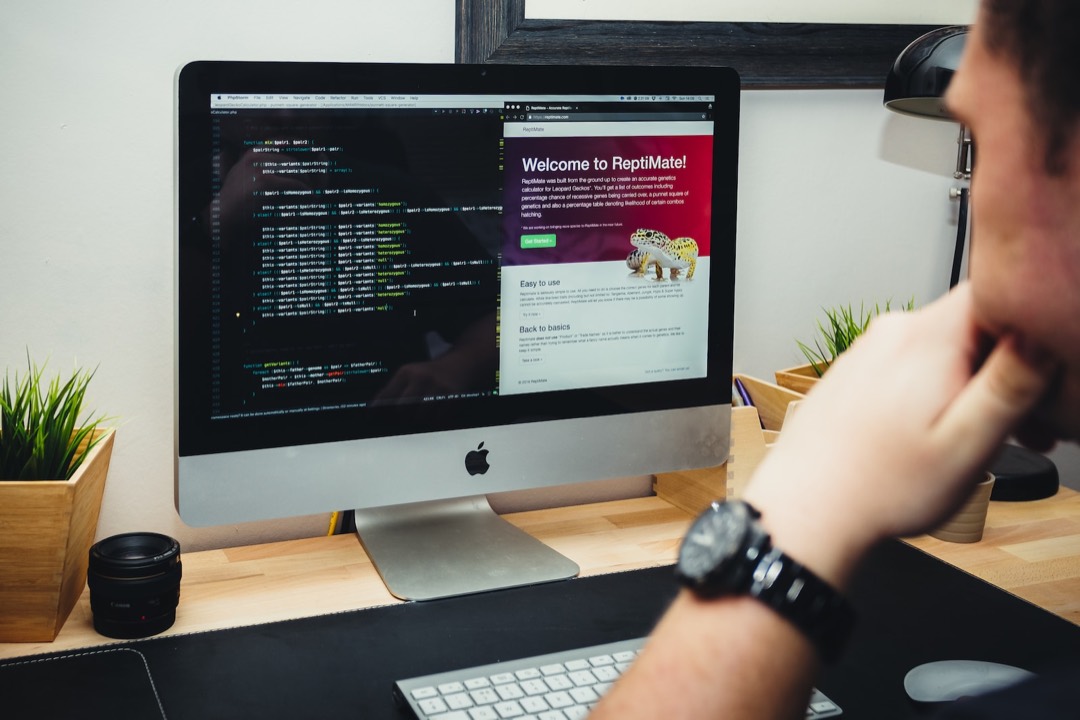 Une personne regarde un écran d’ordinateur qui affiche, à gauche, le code d’un site et, à droite, la page web qui en résulte