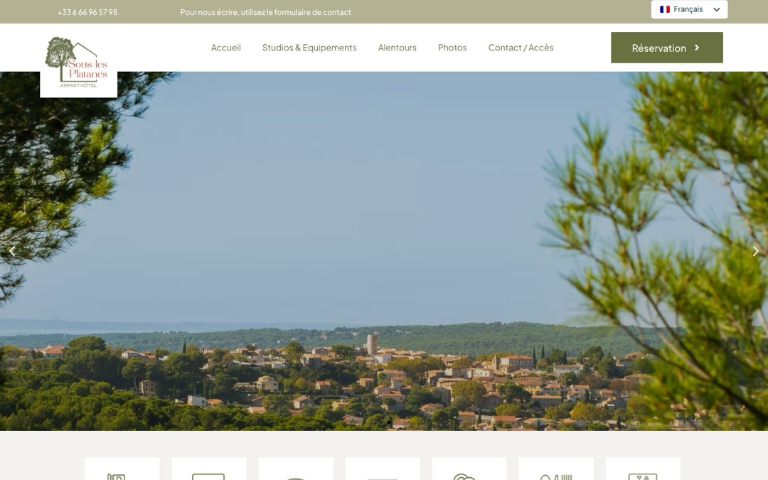 Accueil du site de Sous Les Platanes : photo du village, menu Studios & Équipements, Alentours, Photos et Contact, bouton « Réservation » à droite de l’en-tête
