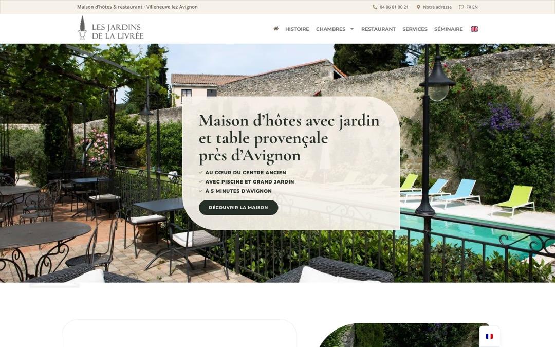 Accueil du site des Jardins de la Livrée : terrasse et piscine derrière un mur de pierre, encadré « Maison d’hôtes avec jardin et table provençale près d’Avignon » et bouton « Découvrir la maison »