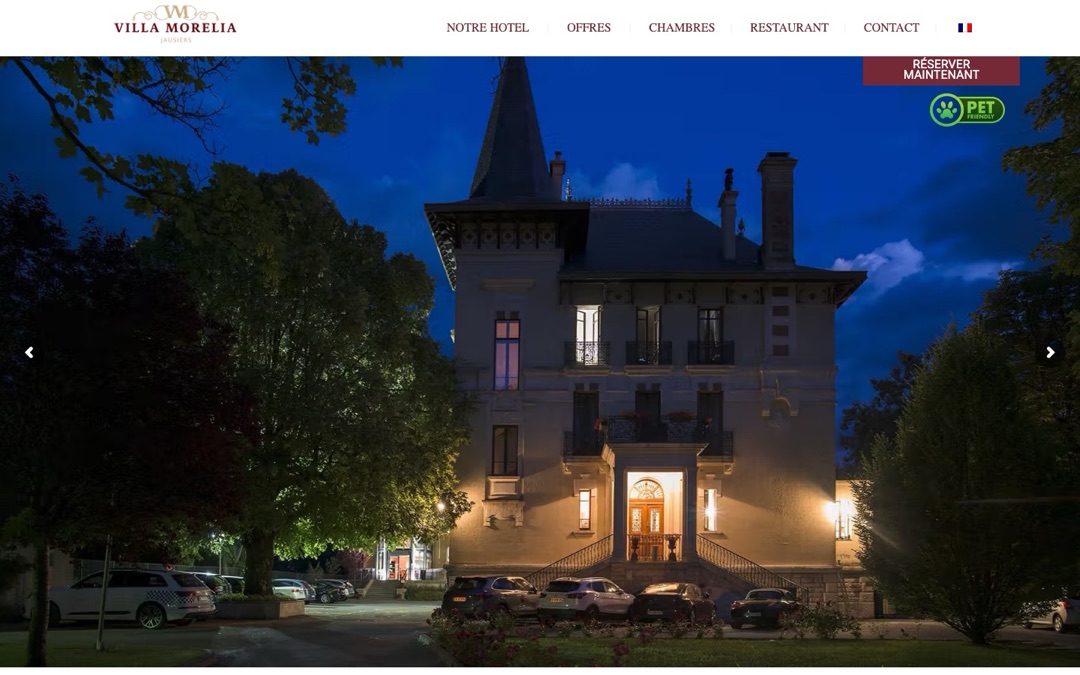 Accueil du site de la Villa Morelia à Jausiers : photo de nuit de la villa éclairée et bouton « Réserver maintenant » fixé en haut à droite