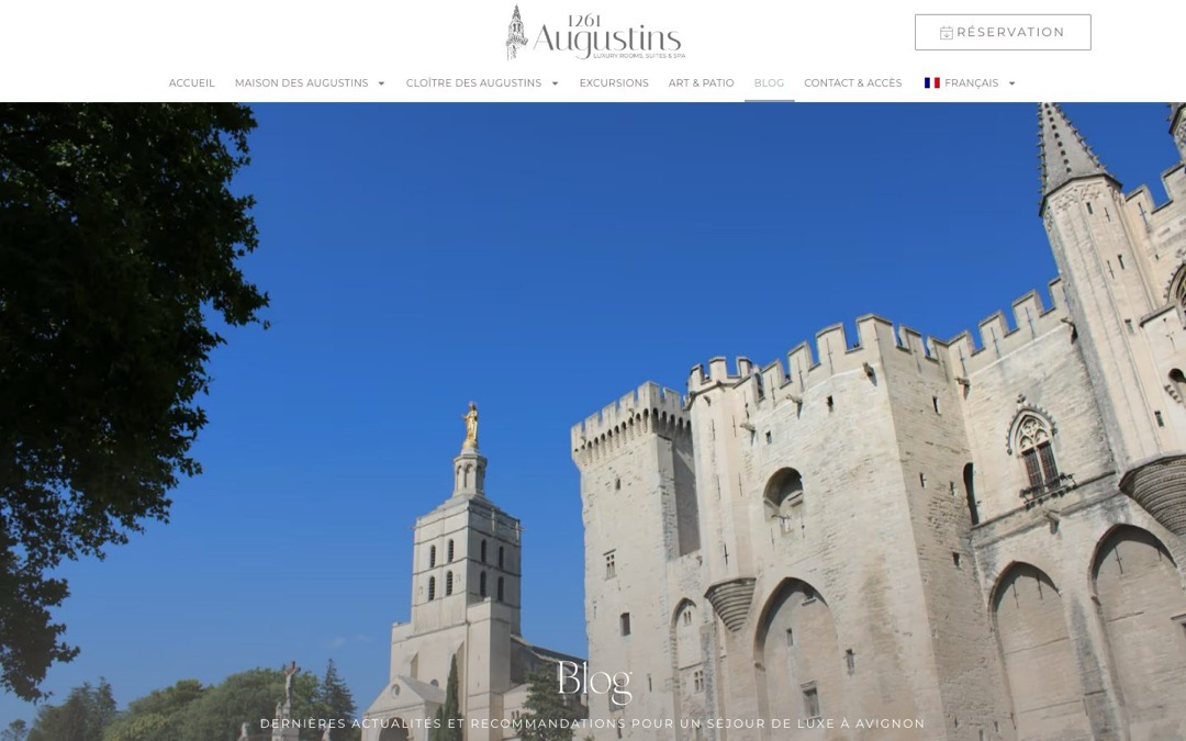 Page « Blog » du site Augustins 1261, à Avignon : menu du site, bouton « Réservation » en haut à droite et photo d’un édifice médiéval à créneaux sous le titre « Blog »