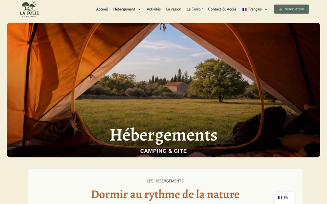 Haut de la page Hébergements du site Aire Naturelle La Folie : vue depuis l’intérieur d’une tente orange ouverte sur une prairie et une bastide en pierre, titre « Hébergements » et mention « Camping et gîte »