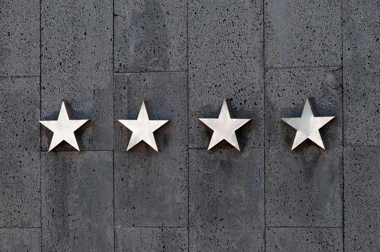Quatre étoiles en métal alignées sur un mur de pierre sombre, comme celles du classement des hôtels
