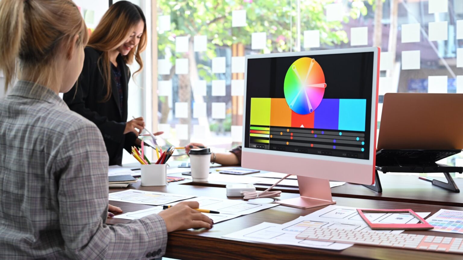 Deux personnes autour d’un écran affichant un nuancier de couleurs, sur un bureau de travail