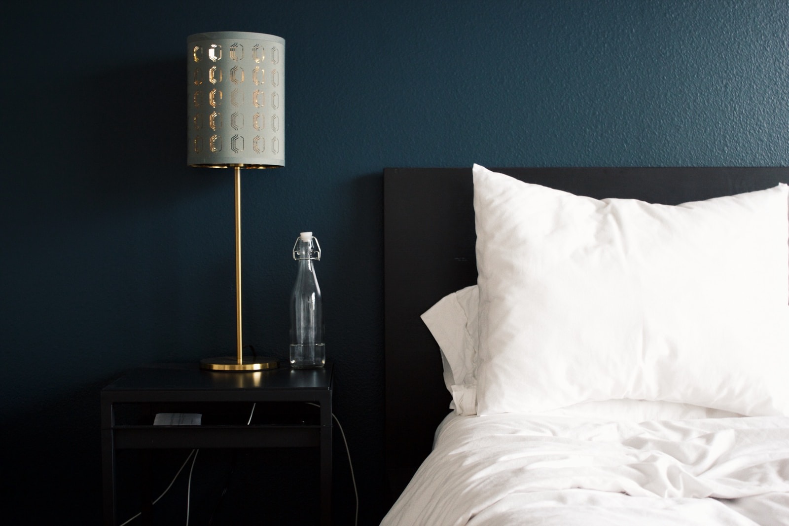 Lit aux oreillers blancs et lampe de chevet dans une chambre aux murs bleu nuit