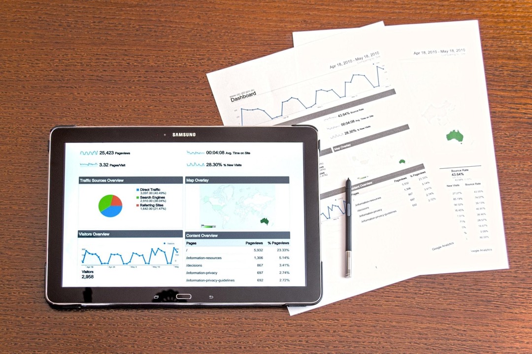 Une tablette affichant un tableau de bord de statistiques de site, posée sur des rapports imprimés