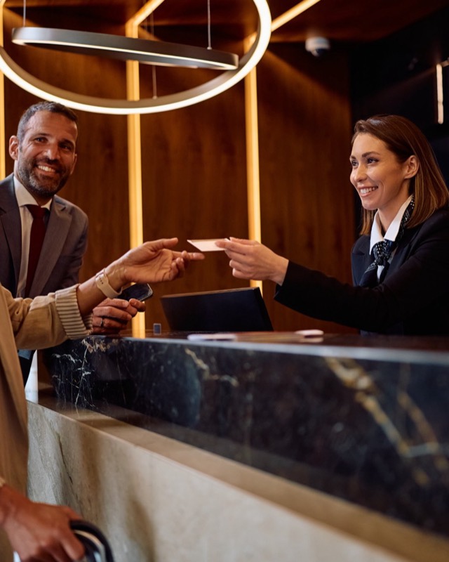 Un client qui règle son séjour à la réception d’un hôtel, face à une réceptionniste souriante