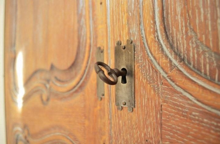Détail d’une armoire ancienne en bois sculpté, avec sa clé dans la serrure