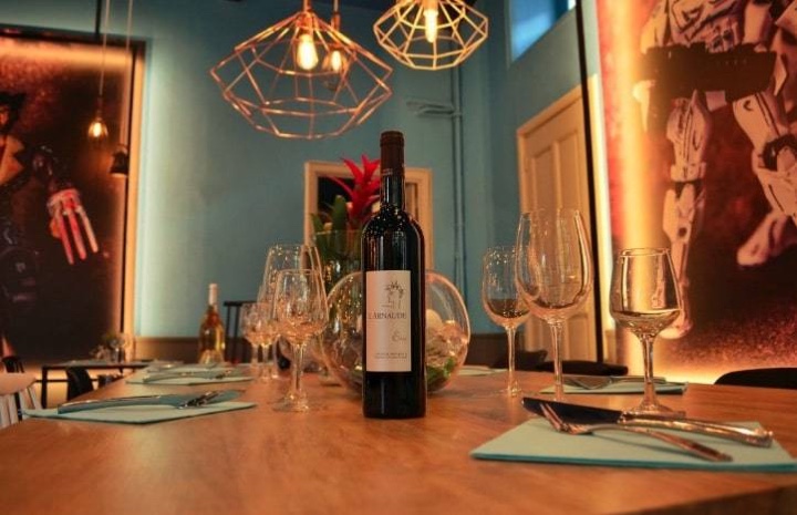 Table dressée avec une bouteille de vin et des verres, sous des suspensions en fil métallique