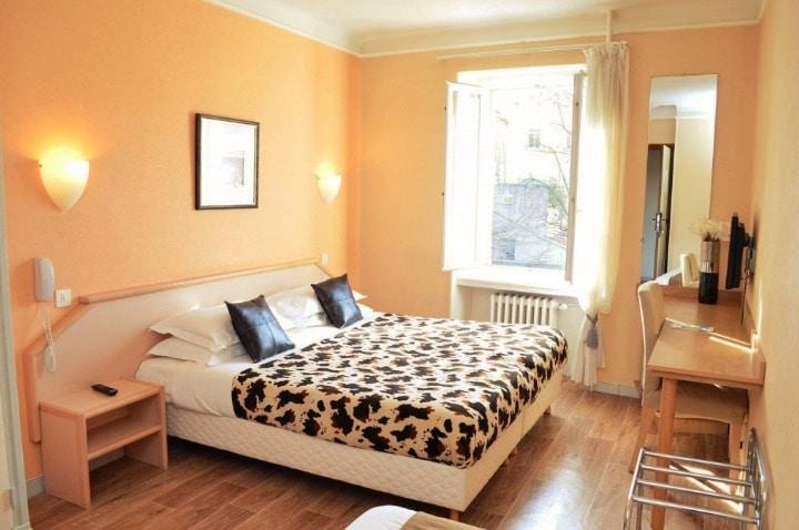 Chambre aux murs orangés avec un grand lit, une fenêtre et un bureau