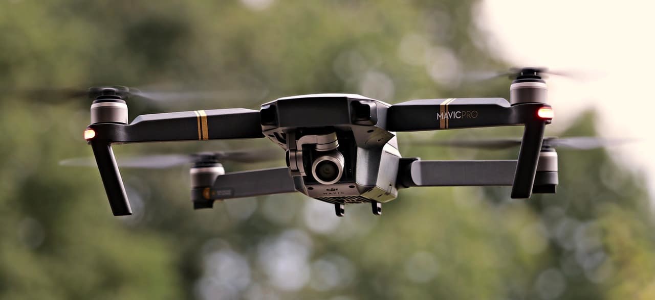 Drone équipé d’une caméra, en vol devant un feuillage